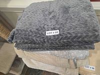 Stack showing grey plush chevron blanket on top, patchwork quilt middle, beige waffle knit bottom