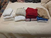 Row of seven folded garments on bed