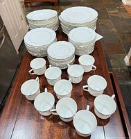 Stacks of plates with cups and saucers laid out on countertop