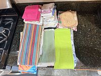 Full lot stacked on counter showing variety of towels, cloths, pot holders