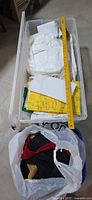 Two plastic bins containing folded and loose fabric pieces with ruler for scale