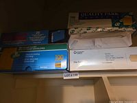 Four retail boxes of folders and envelopes on shelf