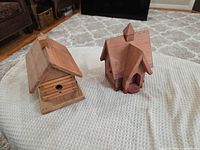 Cabin-style and church-style wooden birdhouses side by side