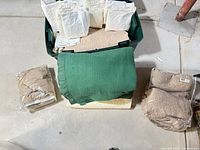 overview of tote with white sheets, green blanket, beige items