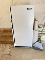 Front view of closed upright freezer showing overall condition, handle, brand badge, and base control strip