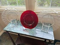 Front view two clear scalloped-edge and one red lattice charger plates on stands