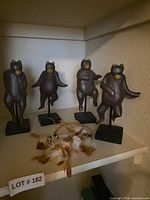All four wooden bear figurines on shelves showing overall condition and presentation