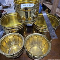 Five brass planters grouped on table; shows styles and finish