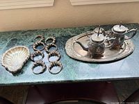 Full lot showing tea set on tray, shell dish, eight napkin rings
