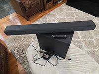 Soundbar on top of subwoofer with remote and cable visible