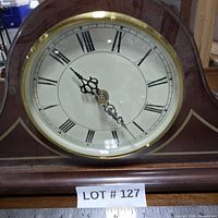 Front close-up of clock dial, brass bezel, Roman numerals