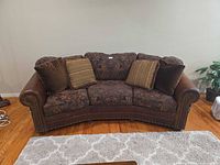 Front view of sofa with pillows showing upholstery and nailhead trim