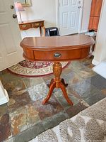 Front view of cherry veneer side table showing drawer, pedestal and tripod base