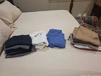 All garments folded on bed showing colors and quantity