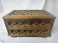 Perspective view showing lattice lid, drawer fronts, knobs, overall form