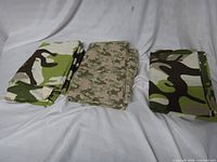 Three folded camouflage cotton sheets displayed on white backdrop