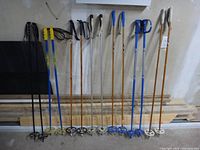 All six pairs of ski poles lined up against wall