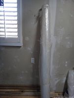 Full view of roll of clear poly leaning against wall