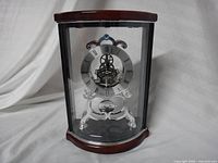 Front three-quarter view showing wood case, curved glass, and skeleton dial