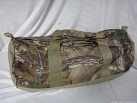 Side view of duffel showing camo pattern, handles and zipper
