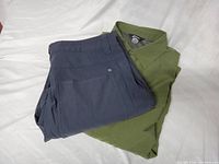 Folded navy convertible pants atop green shirt