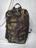 Front view showing camouflage pattern, MOLLE webbing, logo, zippers