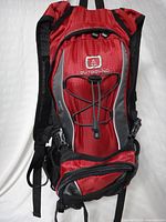 Front of red Outbound Dash backpack with bungee cord and zip compartments