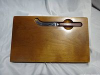 top view of wooden cheese board with knife in recess