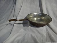Perspective view showing overall pan shape, tin interior, and full length of iron handle
