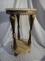 Full view of pedestal table showing marble top, gilt legs, lower shelf, claw feet