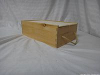 Angled view of wooden storage box showing rope handle and finger-joint construction