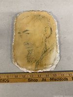 Full view of plaque next to ruler showing size and irregular edges