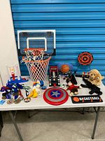 Overview of all items on table including hoop, arcade game, dartboard, plush toys, medals and small toys