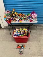 Overall view of table, red bin and clear bin showing bulk of toys