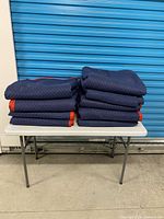 Stack of folded navy blue moving blankets on table