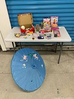 Overview of entire lot on table including umbrella, books, toys and stationery