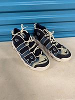 Left side angled view of both sneakers showing AIR lettering, denim colorway, laces and midsole