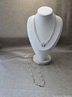 Both necklaces displayed on bust and surface