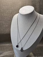 Both necklaces draped on bust showing overall length and pendants
