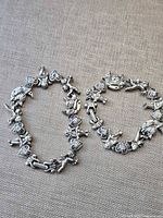Both silver-tone cherub link bracelets displayed side by side