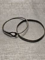 Both bangles laid flat showing overall shapes and bending