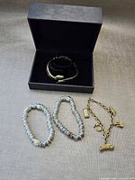 All four bracelets displayed with hinged snake bangle in box, two stretch bracelets and Avon charm bracelet laid out