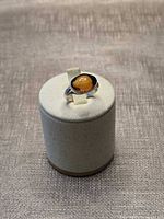 Amber cabochon ring on display stand, frontal view