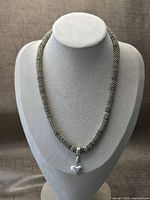 Full view of beaded mesh necklace on bust with heart pendant