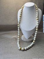 Full view of the necklace displayed on a bust highlighting length and bead pattern