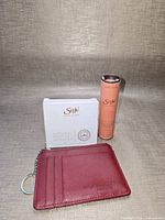 Front view of boxed perfume set, roller tube and wallet