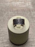 Front view of sterling silver band showing house and figure motifs