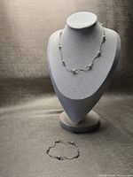 Necklace on bust form; bracelet laid flat below