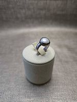 Angled view showing bezel-set mother-of-pearl cabochon and silver-tone band