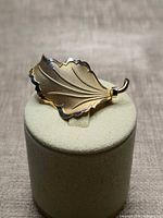 Front view of gold vermeil leaf brooch on display stand